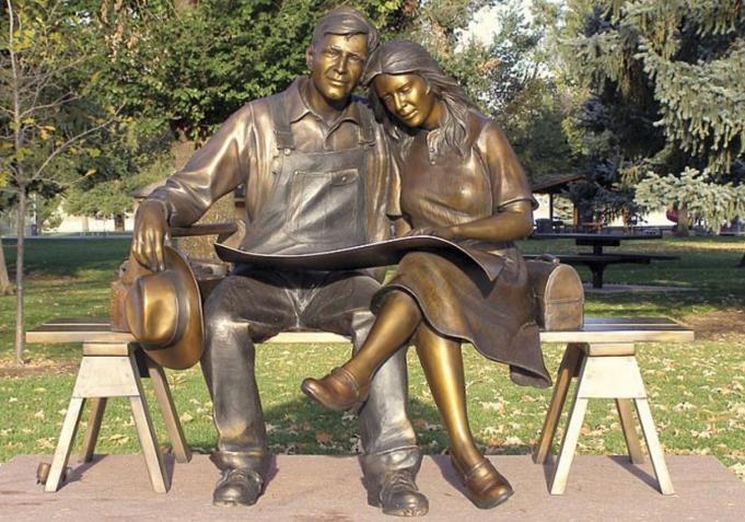 "Hometown" lifesize bronze sculpture of a man and woman sitting on a bench looking at house plans and imaging their future together by Sorrel Sky Gallery artist George Lundeen